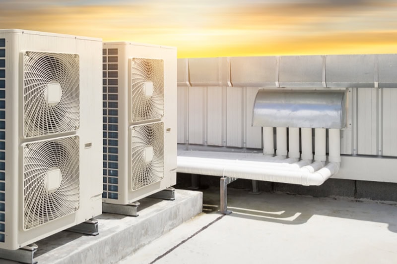 Air compressor machine part of air conditioner system on roof deck with sky background.